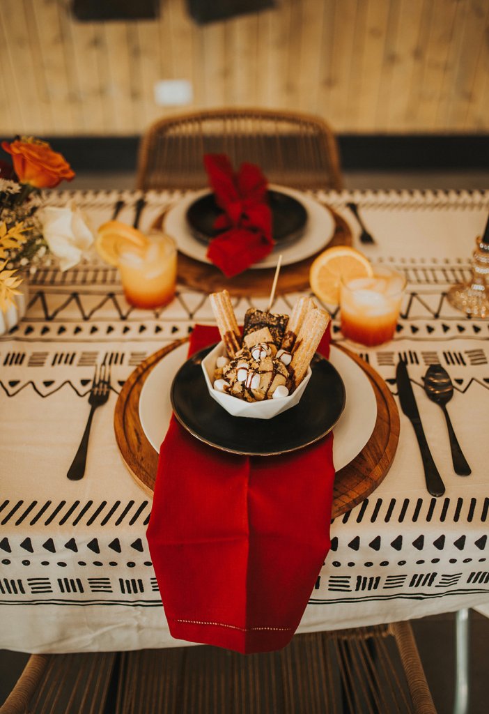 Wedding tablescape with churro dessert plated on red linens.