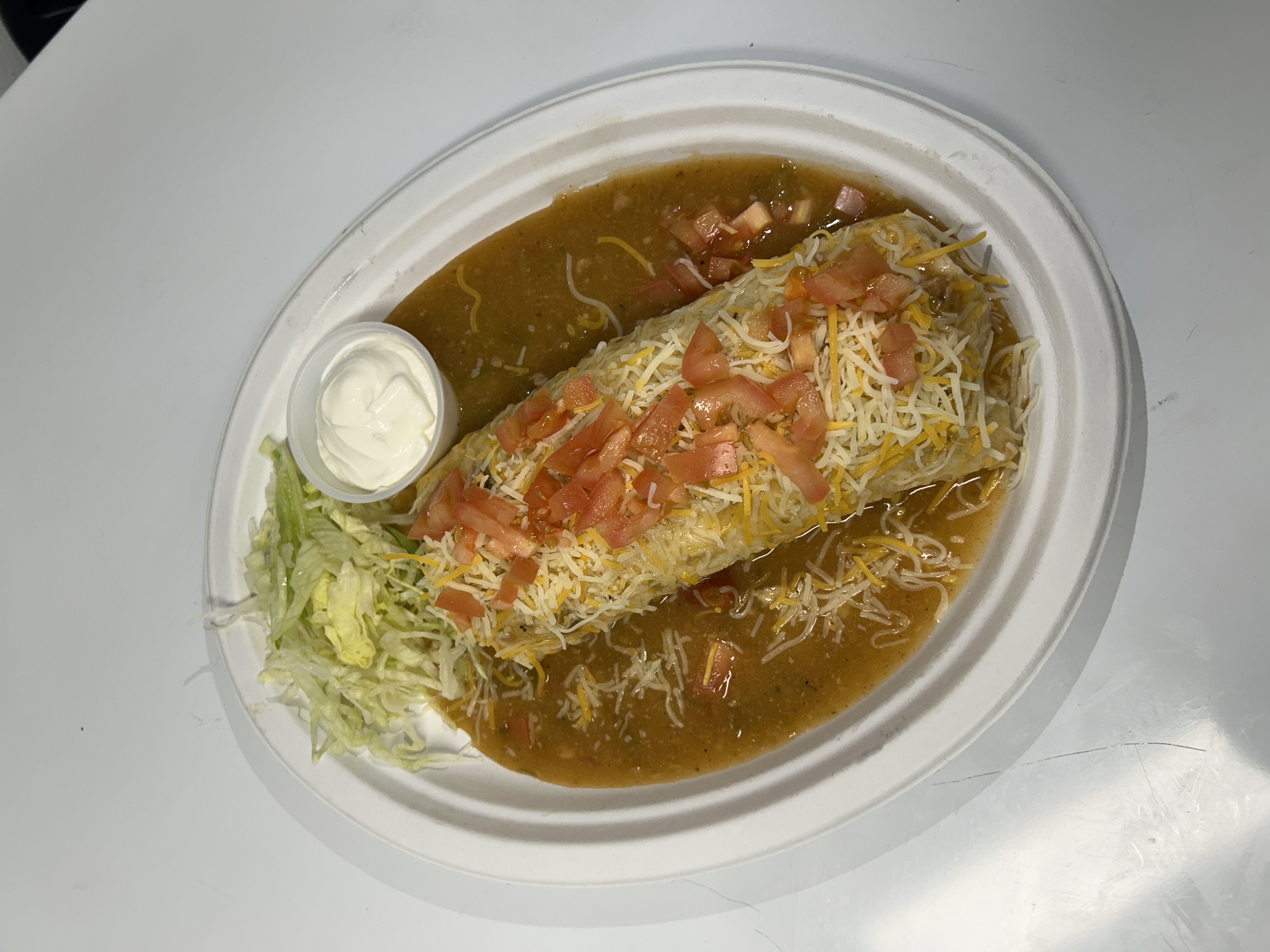 Delicious burrito topped with cheese, tomatoes, and sides.