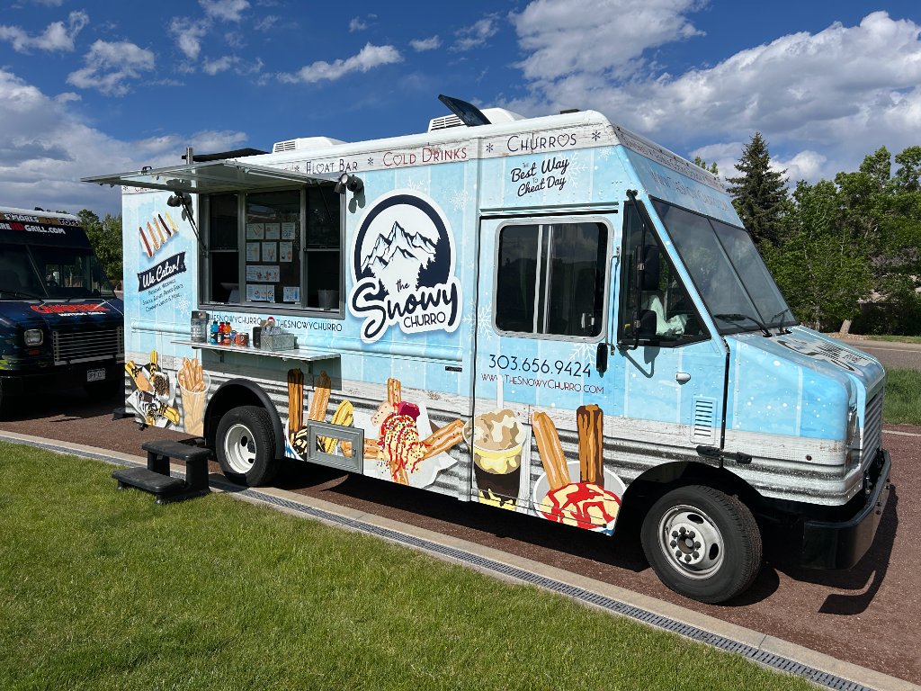 The Snowy Churro food truck parked on a sunny day with branded signage.