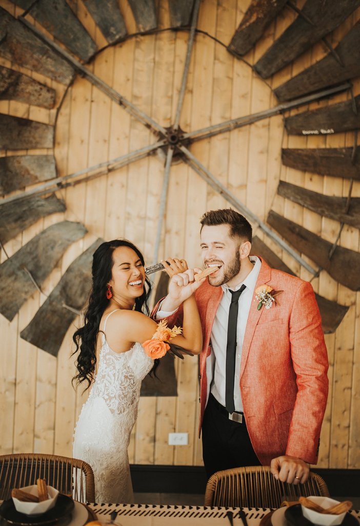 Newlyweds biting into churros together — a sweet wedding moment.