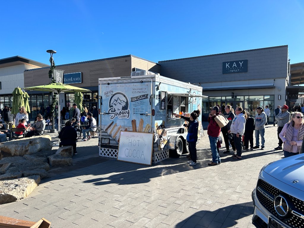Crowd lined up at The Snowy Churro at an outdoor shopping center.
