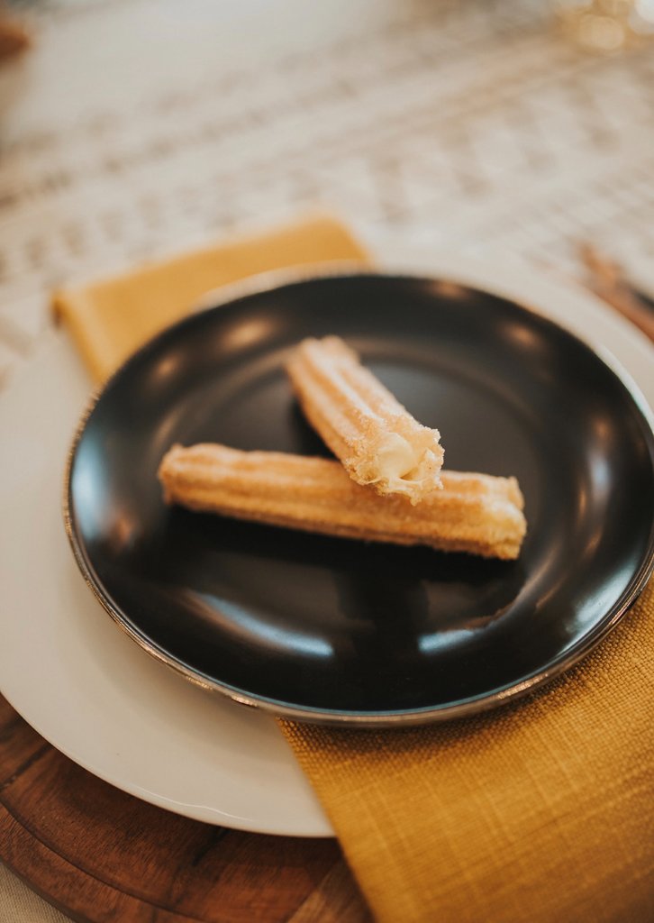 Two churros plated for an elegant wedding dessert course.