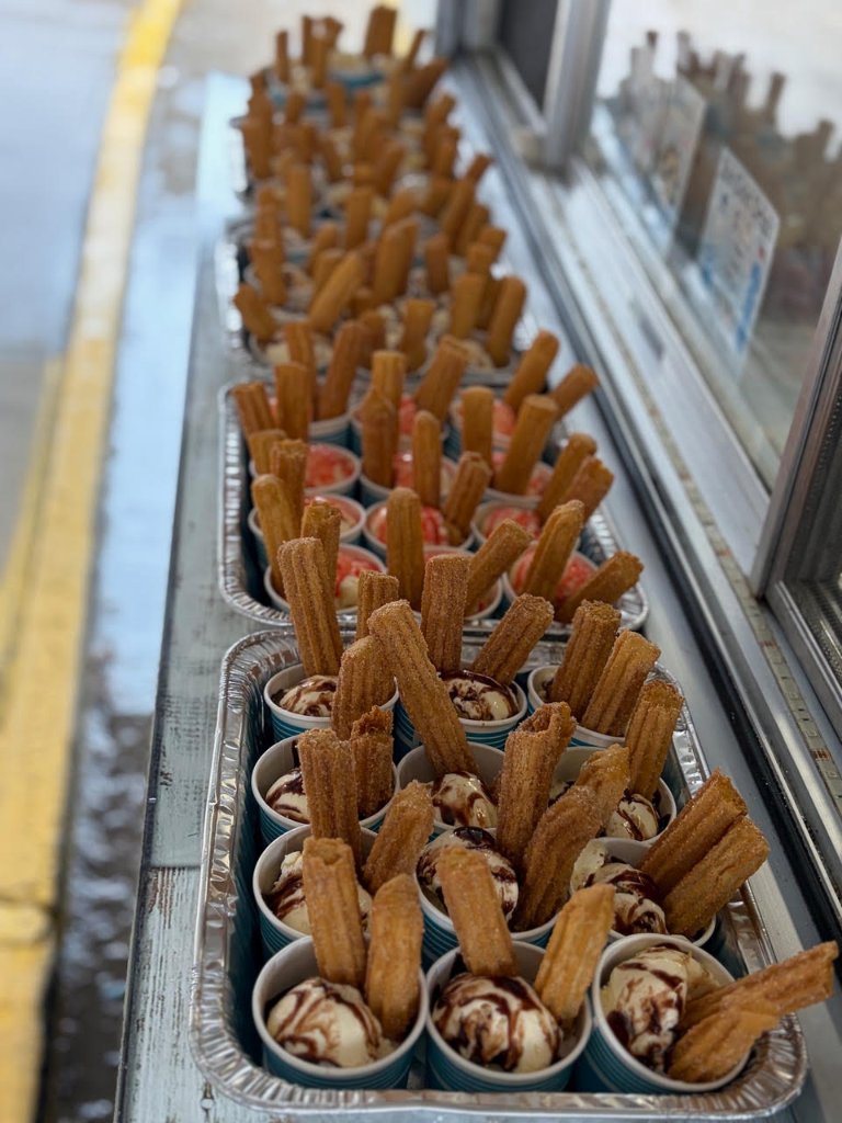 Smiling guest holding two fresh cinnamon-sugar churros at an event.
