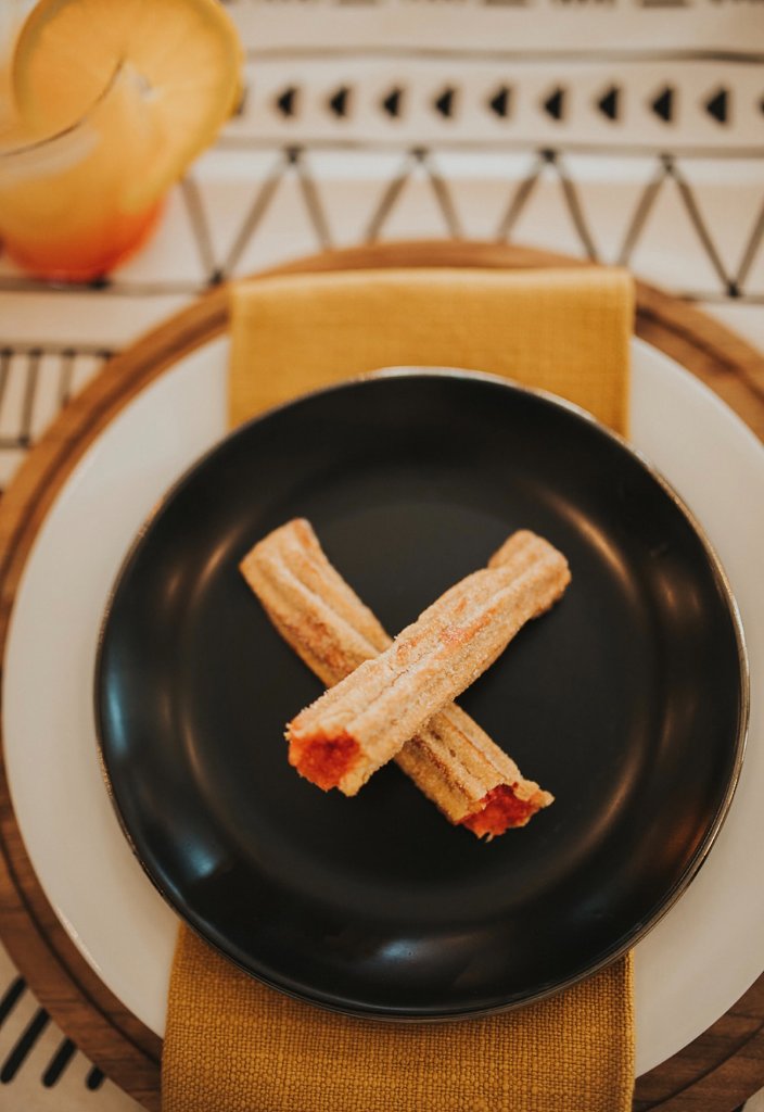 Filled churros plated on a wedding place setting.