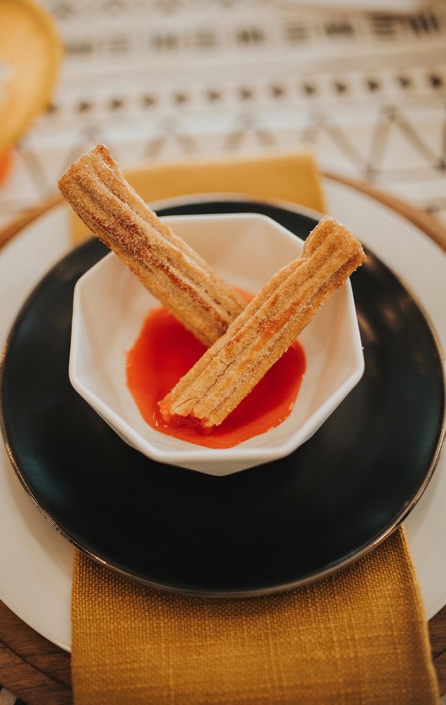 Churros with strawberry dipping sauce styled on a wedding table.