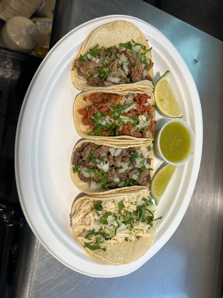 Smothered green chili burrito plated with sour cream and tomatoes.